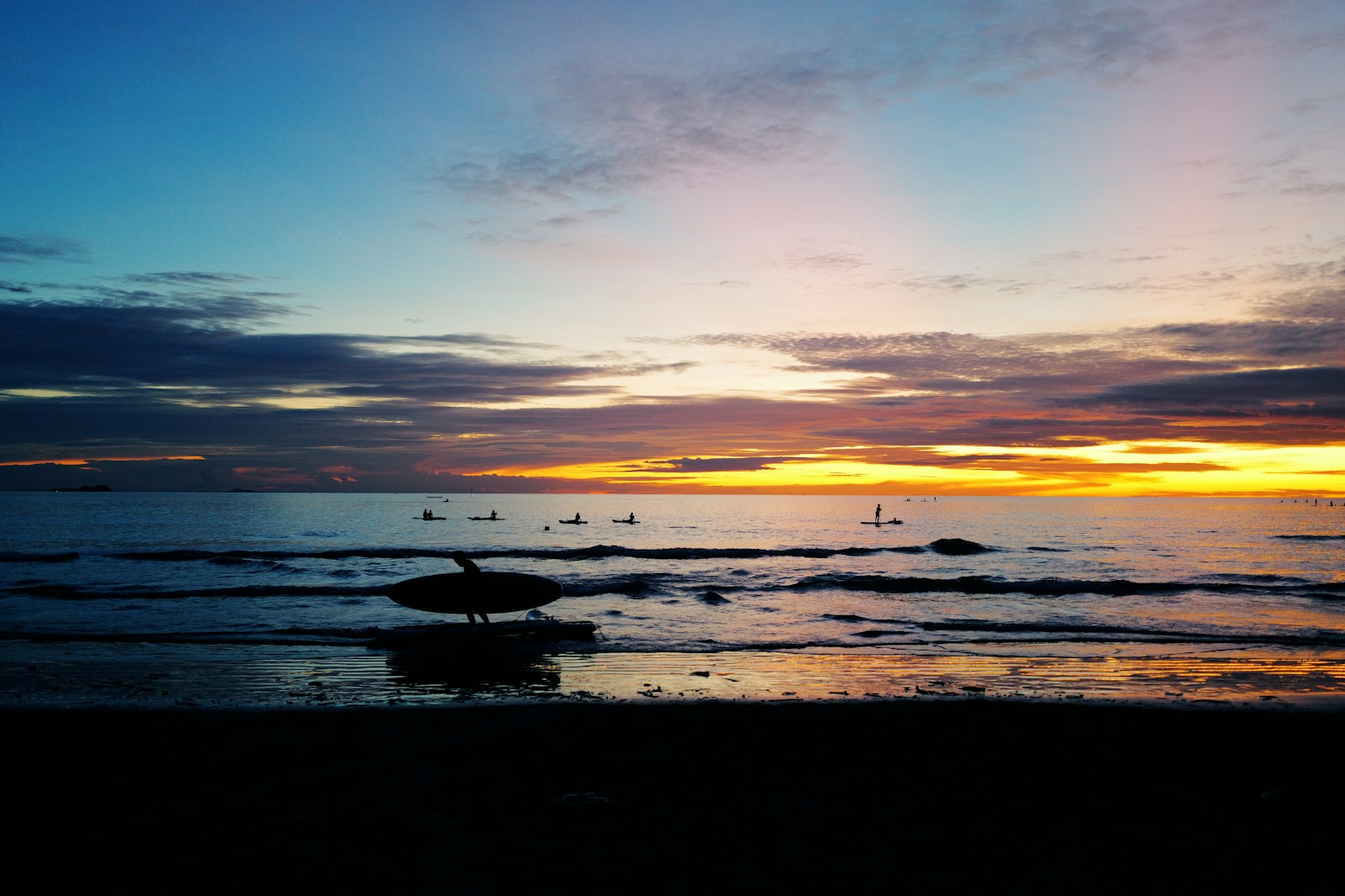 The sun is setting over the ocean with boats in the water